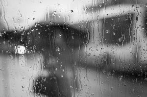 Out of focus figure behind a rain splattered window