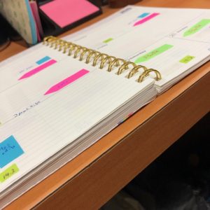 Open planner book with brightly colored sticky note flags throughout the page