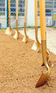 Six gold-painted shovels stuck into dirt