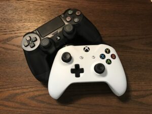 White and black video game controllers on a faux wood surface